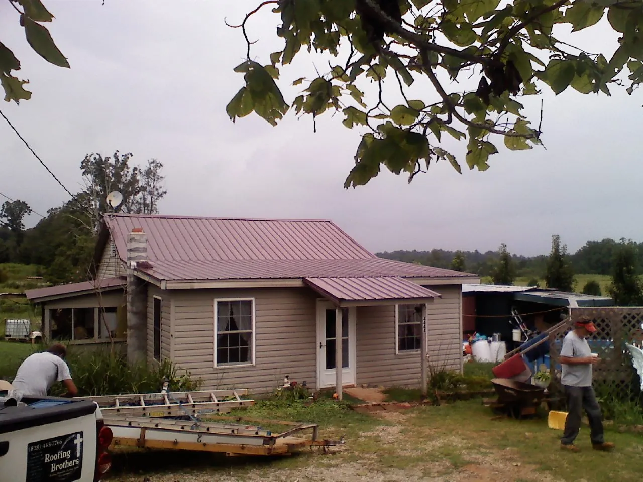 Crew finishing a mauve metal roof on a small farmhouse in Franklinville
